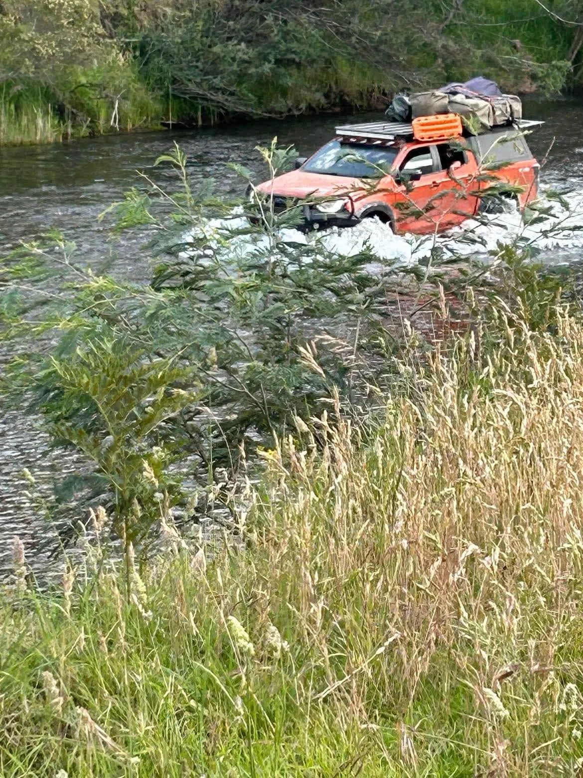Orange 4WD crossing a river on an Australian bush adventure